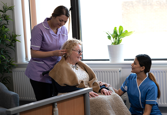 Care workers assisting an elderly woman with personal hygiene
