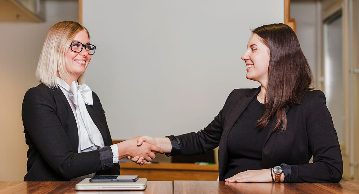 Two women shaking hands after the completion of a care worker interview.