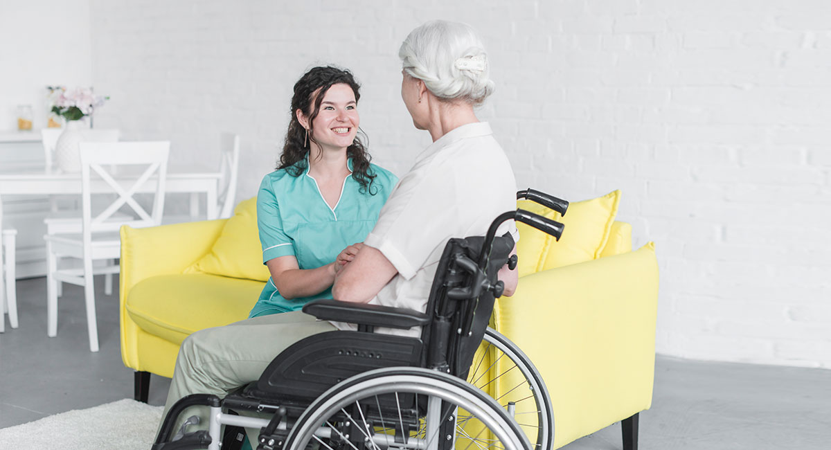 A carer providing domiciliary care to an elderly woman in wheelchair