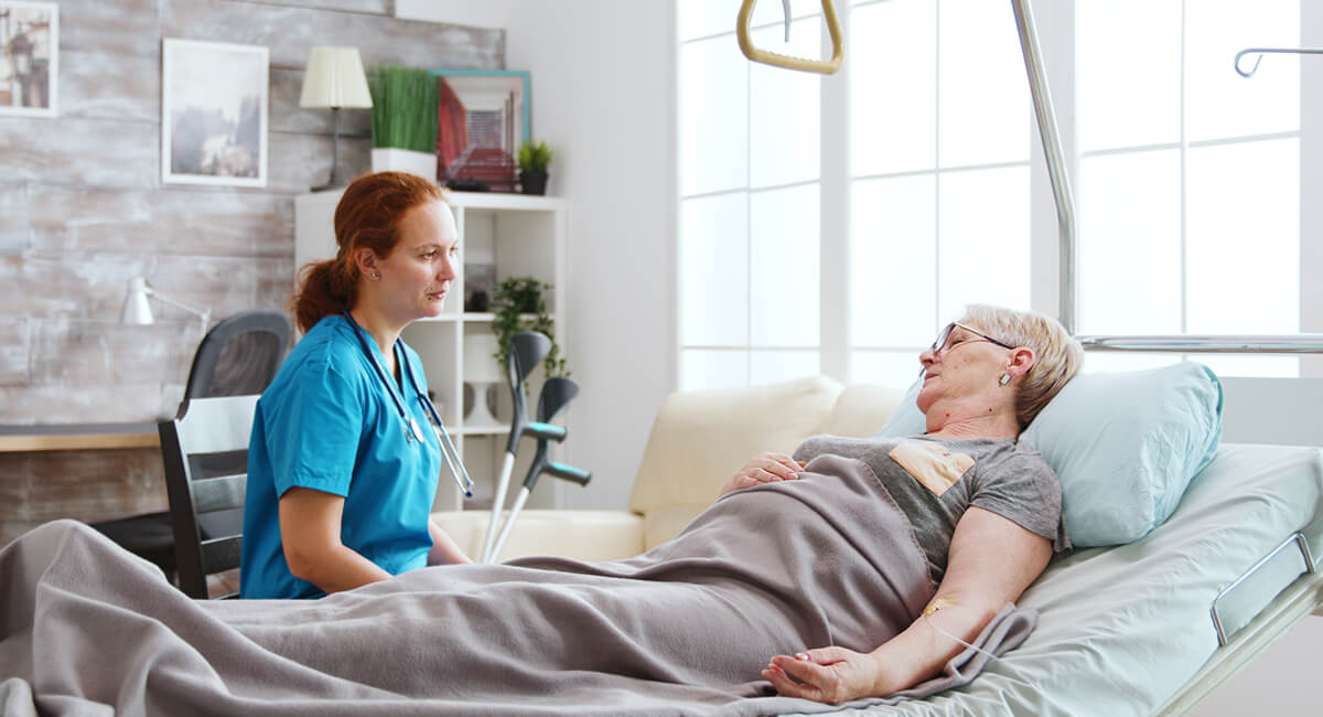 A caregiver providing palliative care service to a bedridden patient.