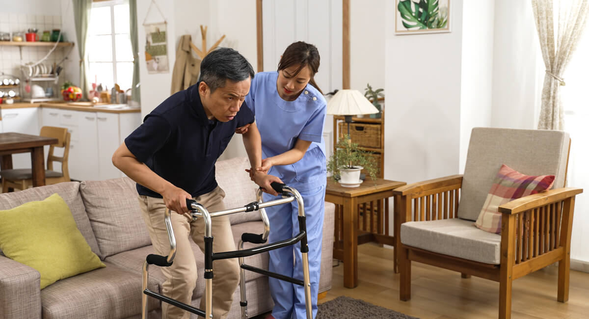 A support worker assisting a senior walking with crutches in her home.