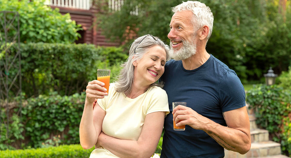 An elderly couple drinking juice in the backyard of their home