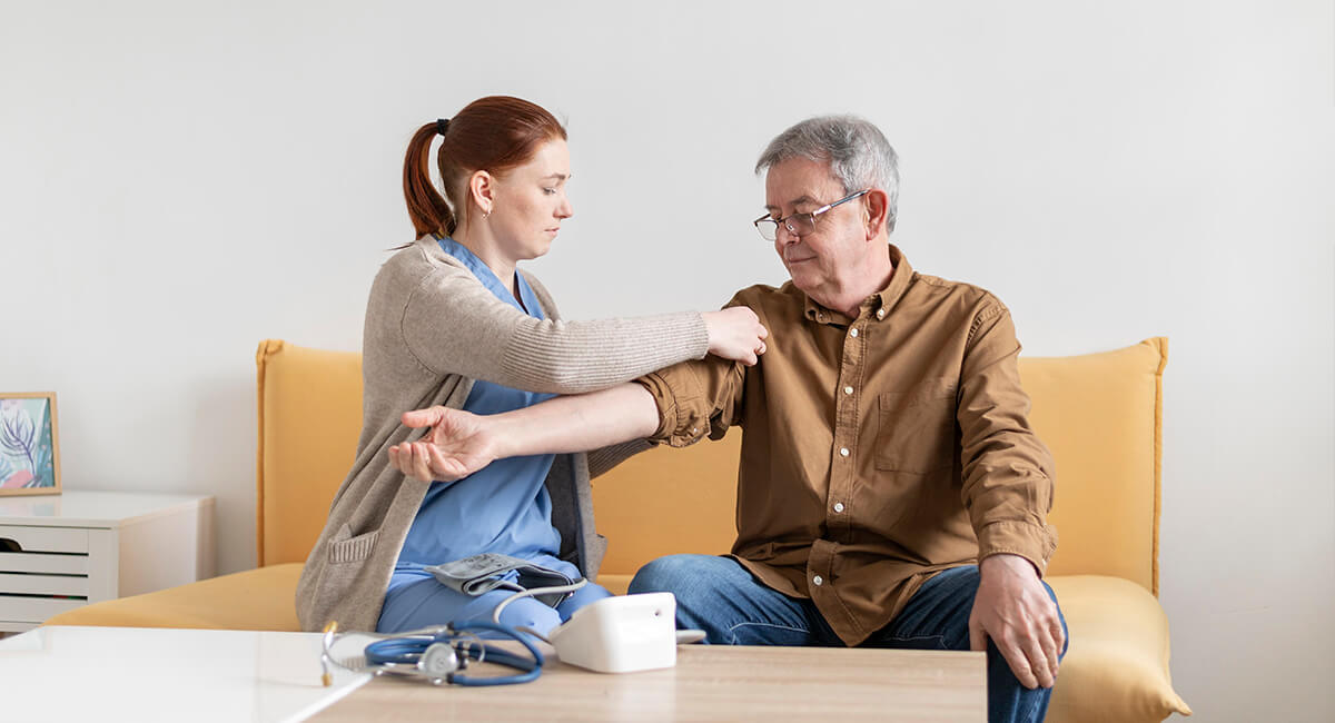 A carer assisting an elderly man at home to manage his medications