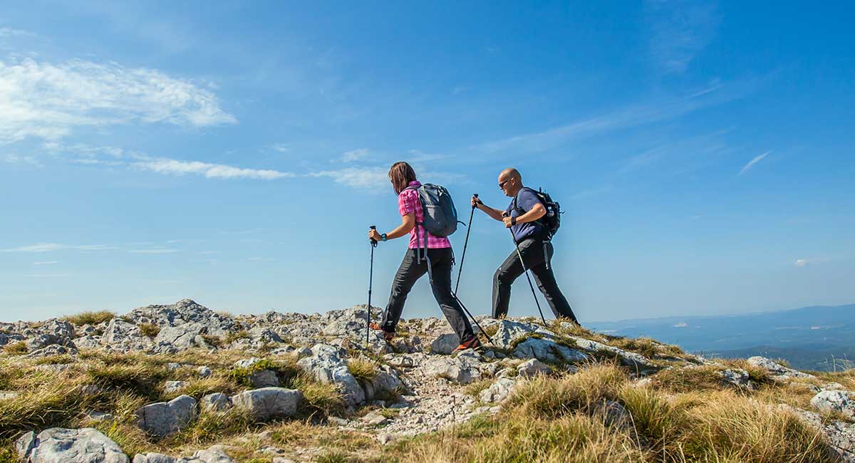 A male and female hiker are depicted on a mountain trek.