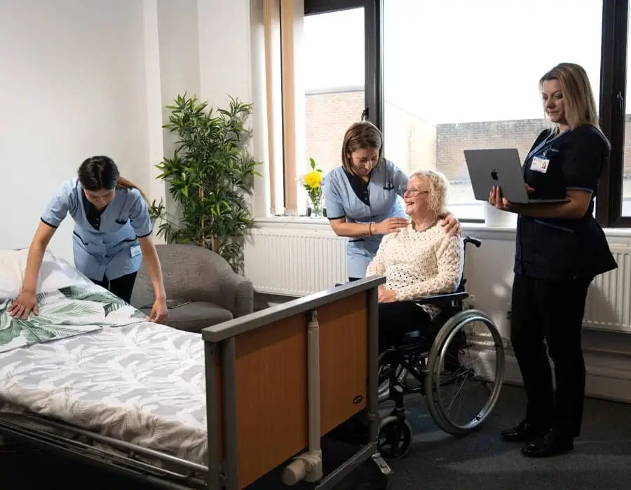 Care workers assist an elderly woman in the late stages of dementia