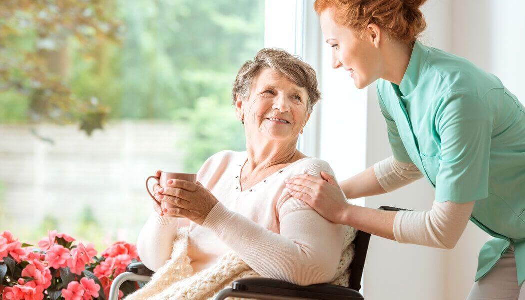 A domiciliary care worker assisting an elderly woman in keeping hydrated