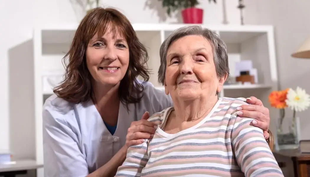 A live-in care assistant reminding an elderly woman to stay hydrated